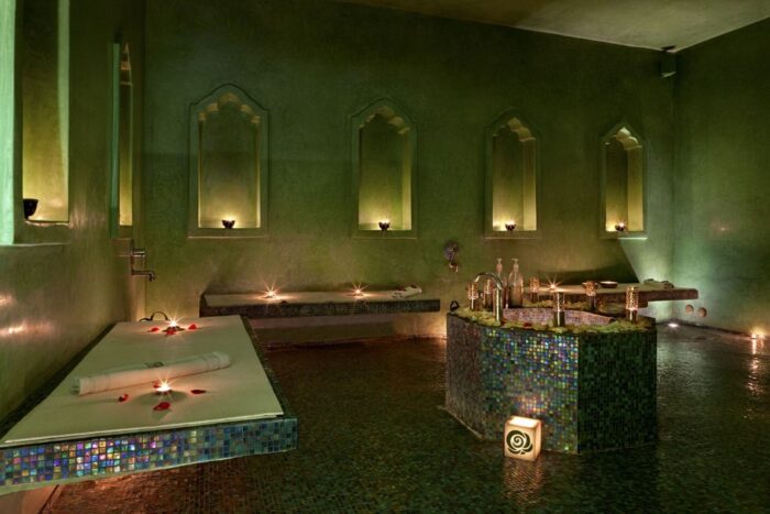 Best Spas and Hammams in Morocco
Share
Tweet

Pin

Morocco is a popular holiday destination in North Africa, known for its striking architecture, sense of history, Islamic culture, delicious gastronomy, colorful souks, arid deserts, and long stretches of coastline with golden sandy beaches along both the Atlantic Ocean and Mediterranean Sea.

Morocco is also a great destination for anyone seeking some blissful relaxation in an opulent spa and an authentic experience in a hammam.

Here is a list of our recommendations of best Spas and Hammams in Morocco

Table of Contents
What is a Hammam?
Best Hammams and Spas in Marrakech
Hammam Dar El Bacha
La Mamounia
Hammam de la Rose
Le Spa Namaskar
Best Hammams and Spas in Casablanca
Hotel Casablanca Le Lido Thalasso and Spa
Gaia Spa
Hammam Ziani
El Jadida
Mazagan Beach & Golf Resort
Oualidia
The Spa at La Sultana
Asni
Asounfou Spa at Kasbah Tamadot
Agadir
O Massage
Sofitel Agadir Thalassa Sea & Spa
Spa Villa Blanche
What is a Hammam?
Hammams are traditional bath houses and steam rooms, and they form a regular part of everyday life for many locals.

The Moroccan hammam traditions stretch back hundreds of years, with people visiting a hammam for a deep cleanse and a social encounter.

A traditional experience involves scrubbing yourself from head to toe whilst in a steam room, with black soap and an exfoliating glove used to remove all dirt and grime and leave your skin feeling soft and smooth.

Some hammams include a massage and / or treatments with the locally produced argan oil.

Hammam Morocco
Hammams have separate areas, or different admission times, for men and women, though some high-class hotels have started to offer treatments for couples, as well as private experiences if you don’t feel comfortable about getting almost naked in a room full of strangers.

Whether you’re looking for a public hamam frequented by locals, a luxury hammam within a tourist-oriented resort, hotel, or Moroccan spa, or a western-style spa with an extensive menu of treatments and techniques, Morocco is sure to not disappoint.

Here are some of the best spas and traditional hamams around Morocco, split into areas of the country:

Best Hammams and Spas in Marrakech
A magnet for tourists and one of the country’s imperial cities, it is easy to enjoy some pampering along with sightseeing and excursions on a holiday in Marrakech.

Hammam Dar El Bacha
This is a top place to visit in Marrakech if you are looking for a taste of a traditional hammam experience. Popular with both locals and tourists, it is located in what was once the public bathhouse.

As with any public hammam you should take along a few essentials, such as soap, shampoo, exfoliating gloves, a brush for your hair, plastic flip flops, a towel, and clean underwear (you will bathe in your underwear, so you need a clean and dry set for afterwards).

There’s a communal changing room where you should strip don to your underwear, and you can leave your bag with an attendant.

You’ll then go into the steam room, where you can take buckets of water to your chosen spot to relax in the heat while your pores open before scrubbing yourself.

If you don’t have a friend with you to scrub your back, you can ask another bather and do theirs in return, or give a small tip to an attendant to clean your back for you.

You can also pay an attendant to scrub your entire body if you’re feeling lazy! With a domed ceiling, ornate doors, and sweeping arches, it’s rather a pretty public hammam.

La Mamounia
Hammam, La Mamounia
La Mamounia Hotel, Marrakech, Morocco. Photo by Alan Keohane www.still-images.net for La Mamounia
On the opposite end of the scale, La Mamounia is a luxury hammam and spa within an opulent five-star hotel of the same name.

One of the top hotels in Marrakech, La Mamounia is steeped in history and you cannot help but feel special from the moment you walk through the doors.

The spa and wellness facilities are open to non-guests, though advance bookings are recommended.

The spa has a large and luxurious hammam where you can unwind and cleanse in the most stunning surroundings.

Alternatively, the spa offers a range of pampering treatments, including various types of massages, body scrubs, body wraps, and facials.

There’s also a Jacuzzi, a swimming pool, and a fitness centre.

If you’re feeling particularly flush, you can even hire an entire mini spa all to yourself, complete with a private changing room, a treatment room with two tables, a shower, a private Jacuzzi, and an intimate hammam, all surrounded by warm hues of orange and red and exquisite mosaics.

Don’t leave without also visiting the hair and beauty salon for the ultimate in looking and feeling great.

Hammam de la Rose
Hammam Marrakech
Within the old part of the city, you’ll find the lovely Hammam de la Rose within the medina’s high walls.